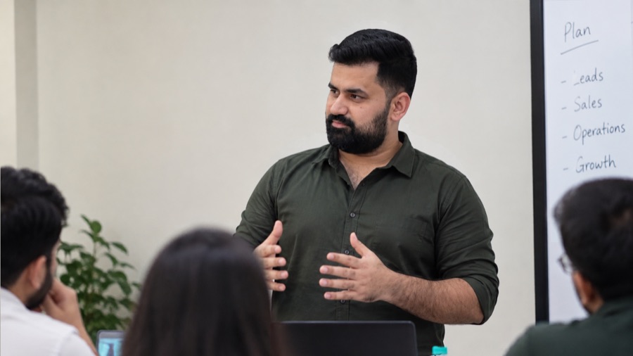 Weyuu's founder talking a small business team through a growth plan, with Leads, Sales, Operations and Growth listed on the board behind him